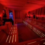 Group enjoying a lively sauna session at MindFuel’s Strip District studio with red ambient lighting