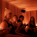 Four women smiling and laughing together in the largest sauna in Pittsburgh at MindFuel Method