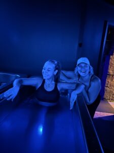 Two women smiling at the cold plunge tub at MindFuel in Pittsburgh's Strip District