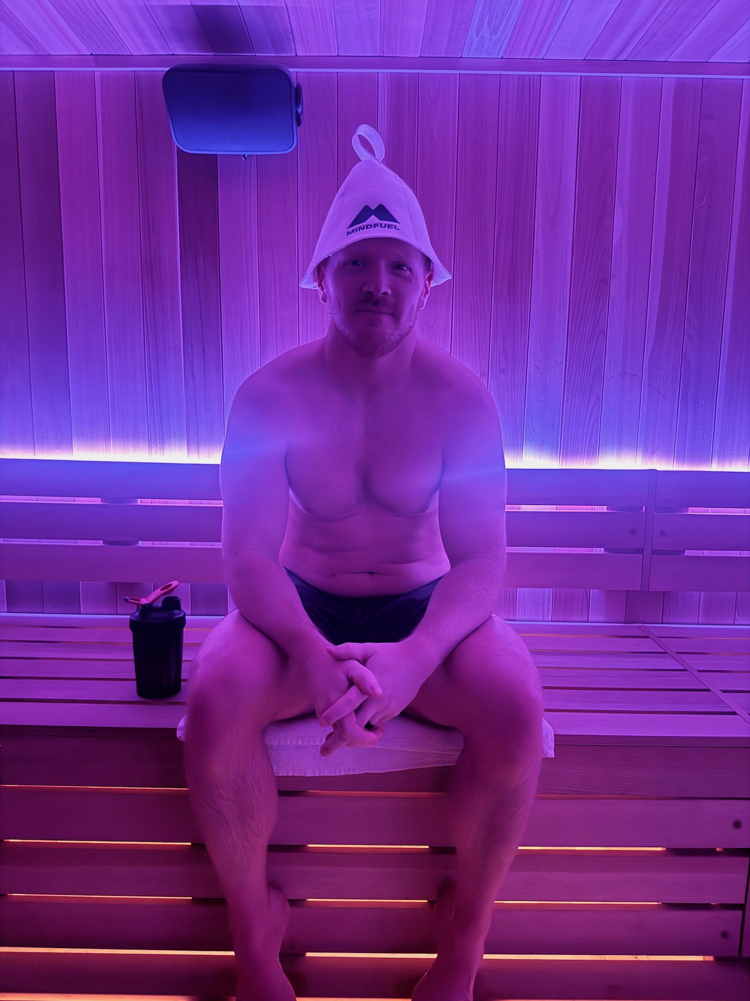 Man wearing a white wool MindFuel sauna hat in the traditional Finnish sauna at MindFuel in Pittsburgh