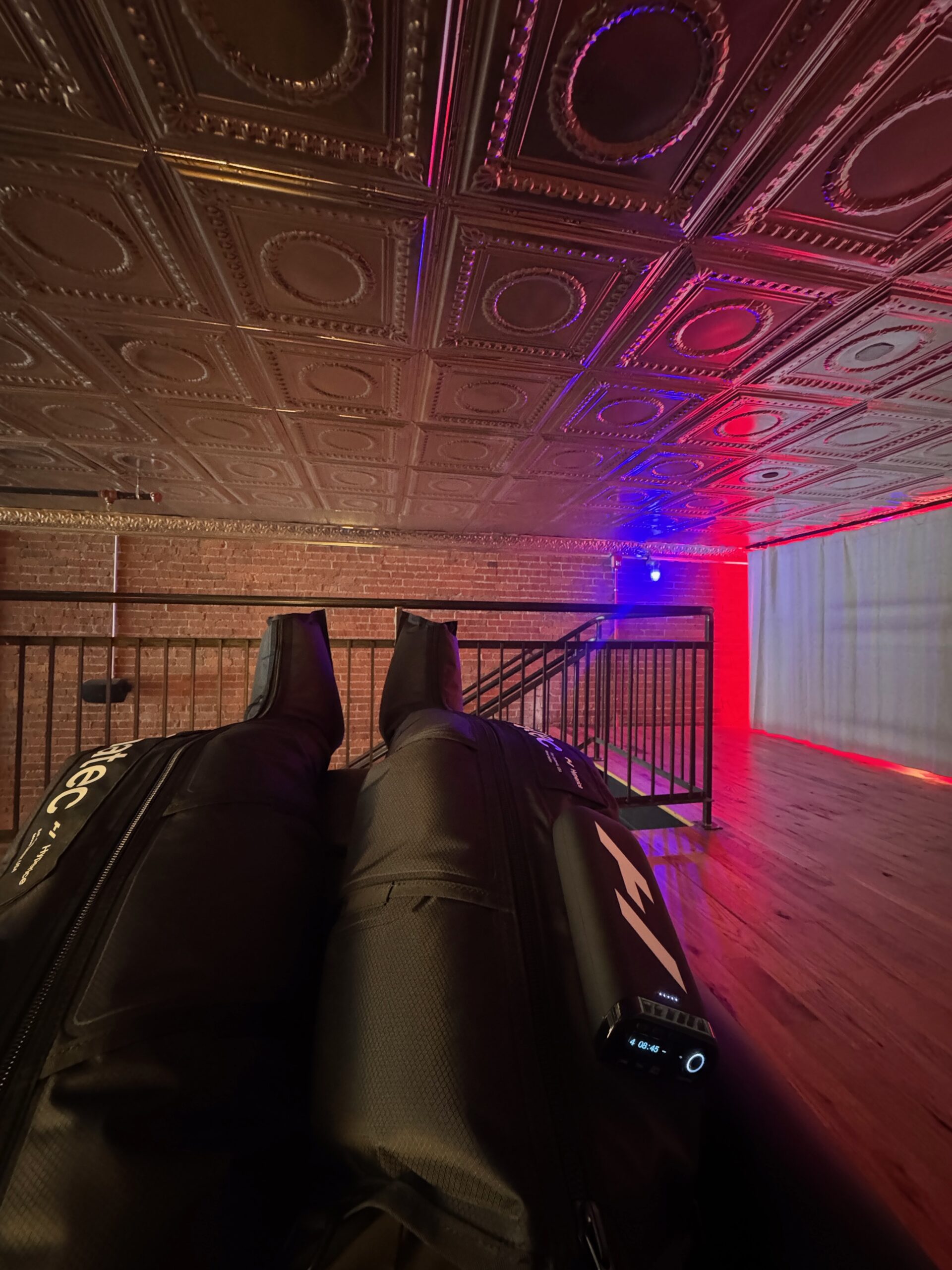 First-person view of Normatec compression boots on the Recovery Lounge mezzanine at MindFuel Method in Pittsburgh