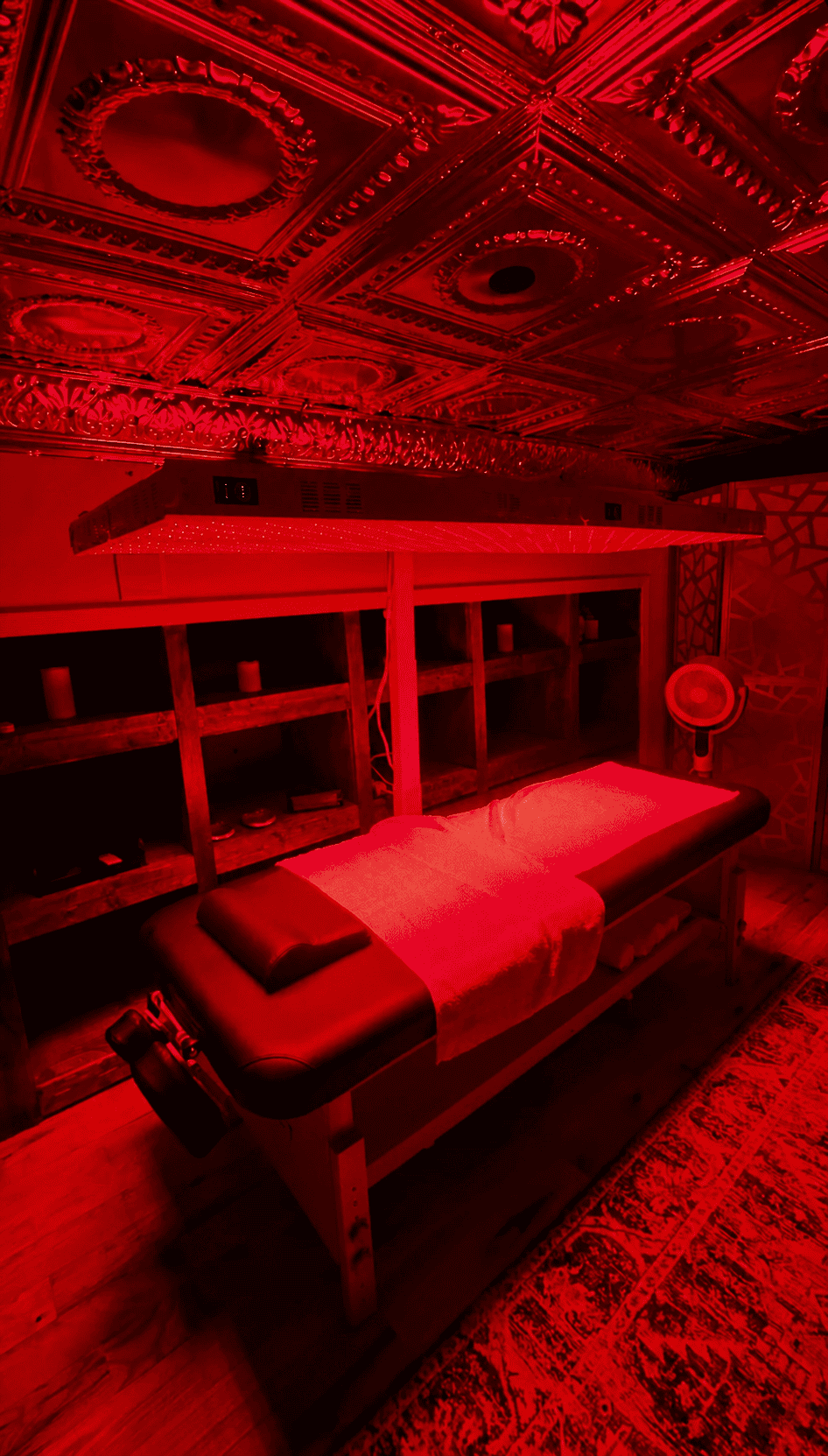 Red light therapy treatment table bathed in red glow under clinical-grade panels at MindFuel Method Recovery Lounge in Pittsburgh
