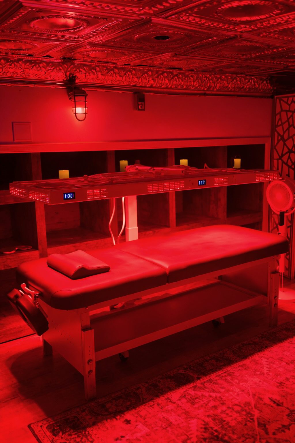 Red light therapy room at MindFuel Method Recovery Lounge featuring clinical-grade panels, treatment table, tin ceiling, and warm ambient lighting in Pittsburgh